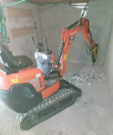 Mini excavadora picando suelo de cemento