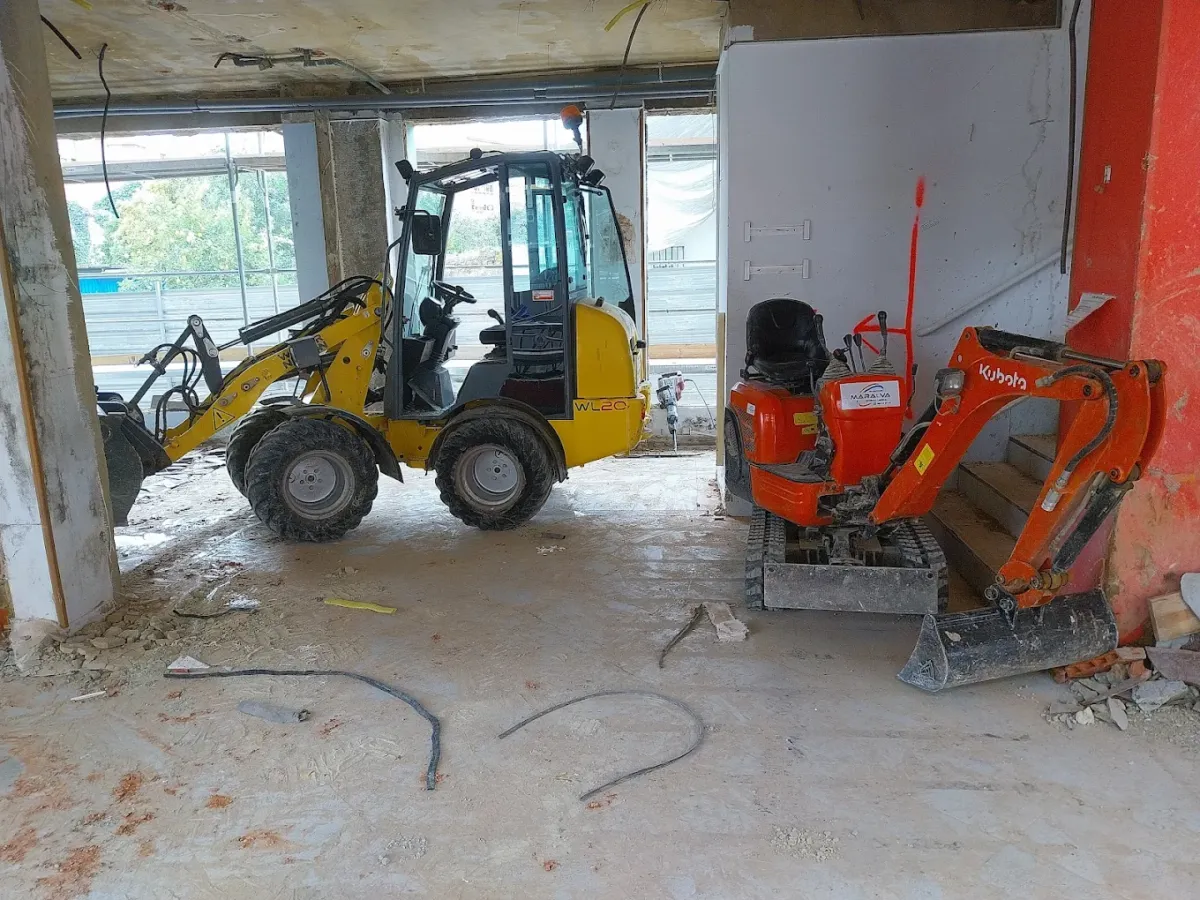 Una mili pala y una mini excavadora en el interior de una obra