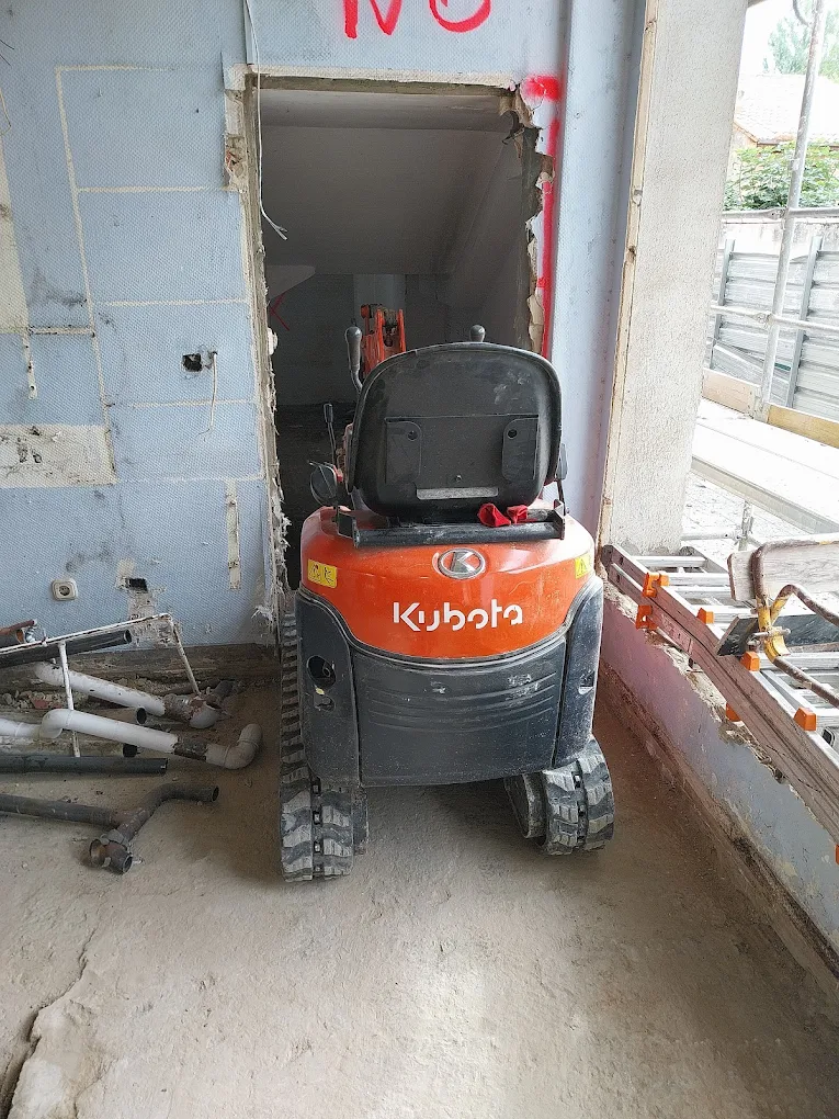 Miniexcavadora entrando por una puerta en una obra interior