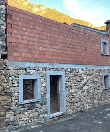 Obra de construcción de una fachada de una casa con piedra y ladrillo